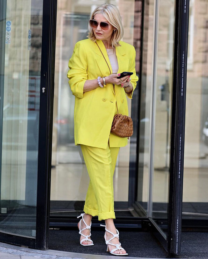 Woman in a bright yellow matching blazer-and-trouser suit with sandals